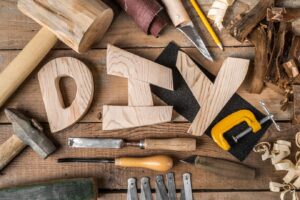 flat lay of woodworking tools and materials, including wooden letters spelling "DIY"