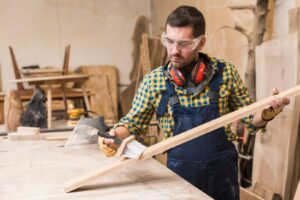 craftsman in a workshop applies paint to a wooden plank