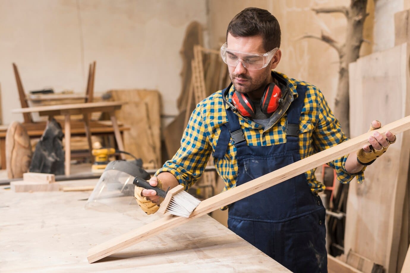 craftsman in a workshop applies paint to a wooden plank