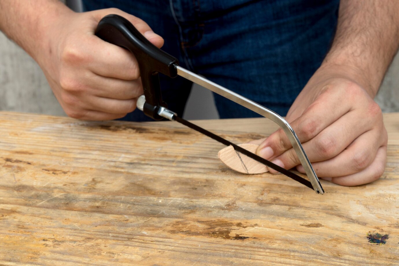  person uses a coping saw to cut a wooden piece