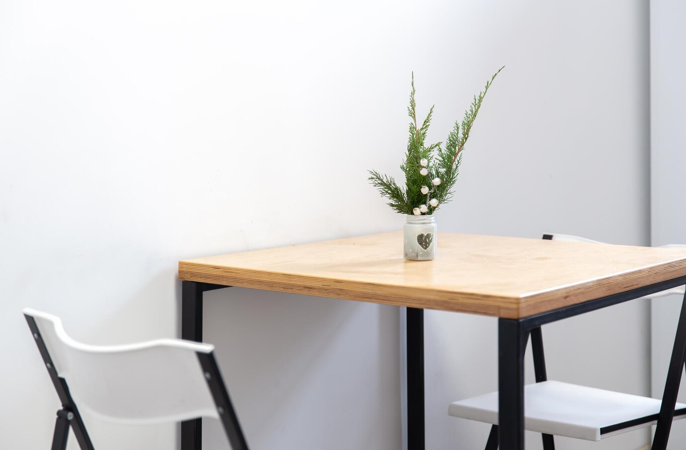  minimalist wooden table with a heart-decorated vase holding green foliage