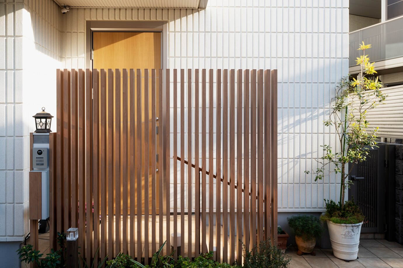 A wooden slatted fence surrounds a modern wooden door