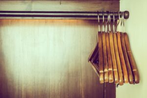 series of wooden hangers suspended on a metal rod against a warm-toned