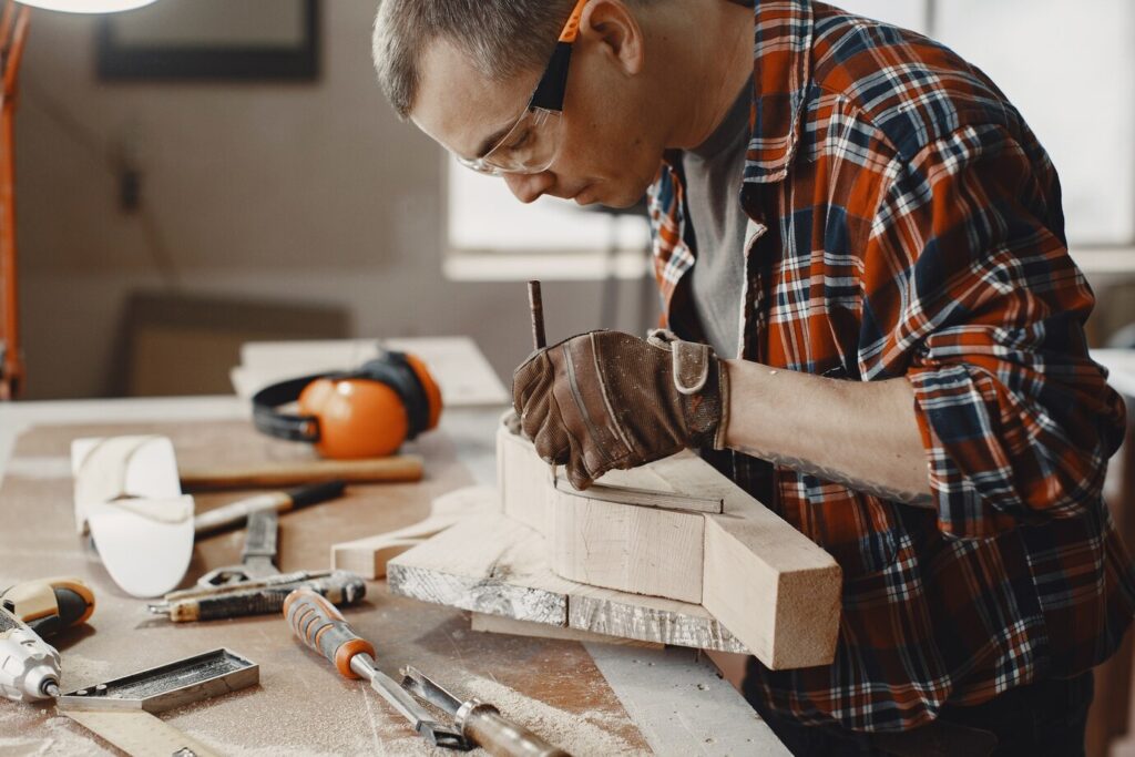 craftsman in a plaid shirt works on a wooden project