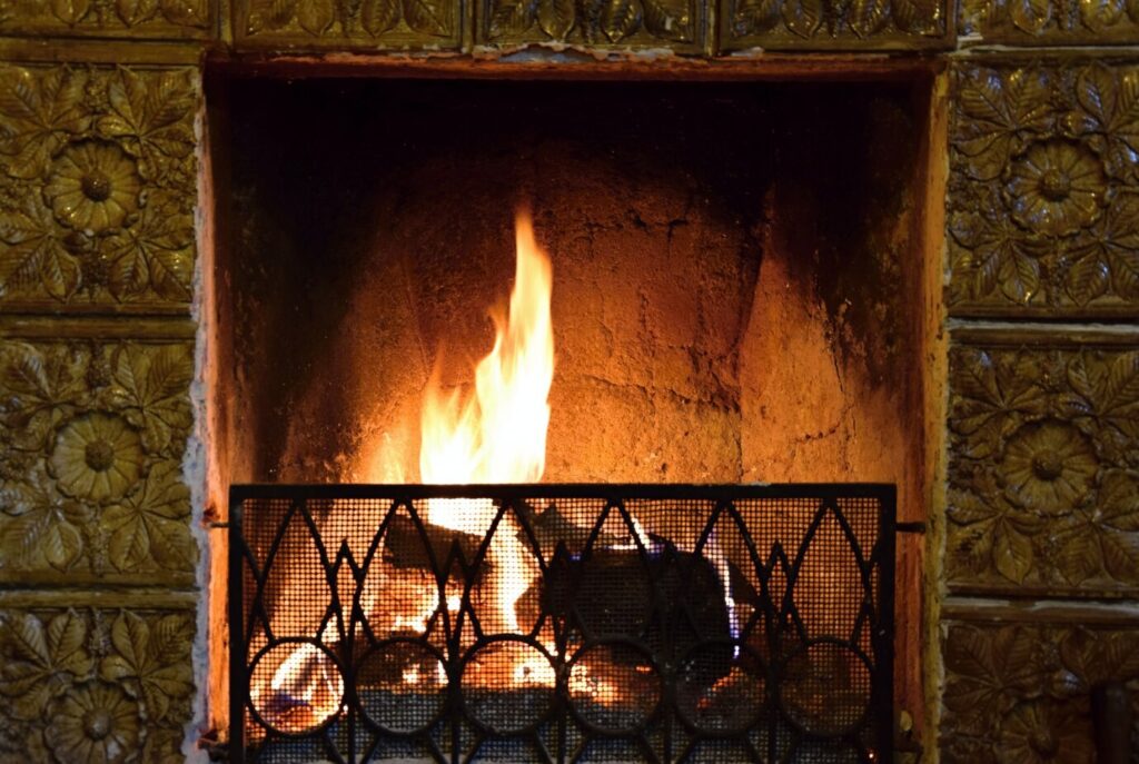 A cozy fireplace with flickering flames behind a metal grate