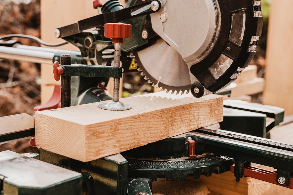  close-up of a circular saw on a miter saw, poised to cut a wooden plank