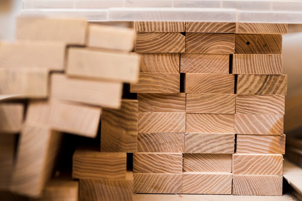 Neatly stacked wooden blocks displaying a variety of natural wood grains, arranged in a tidy workshop setting.